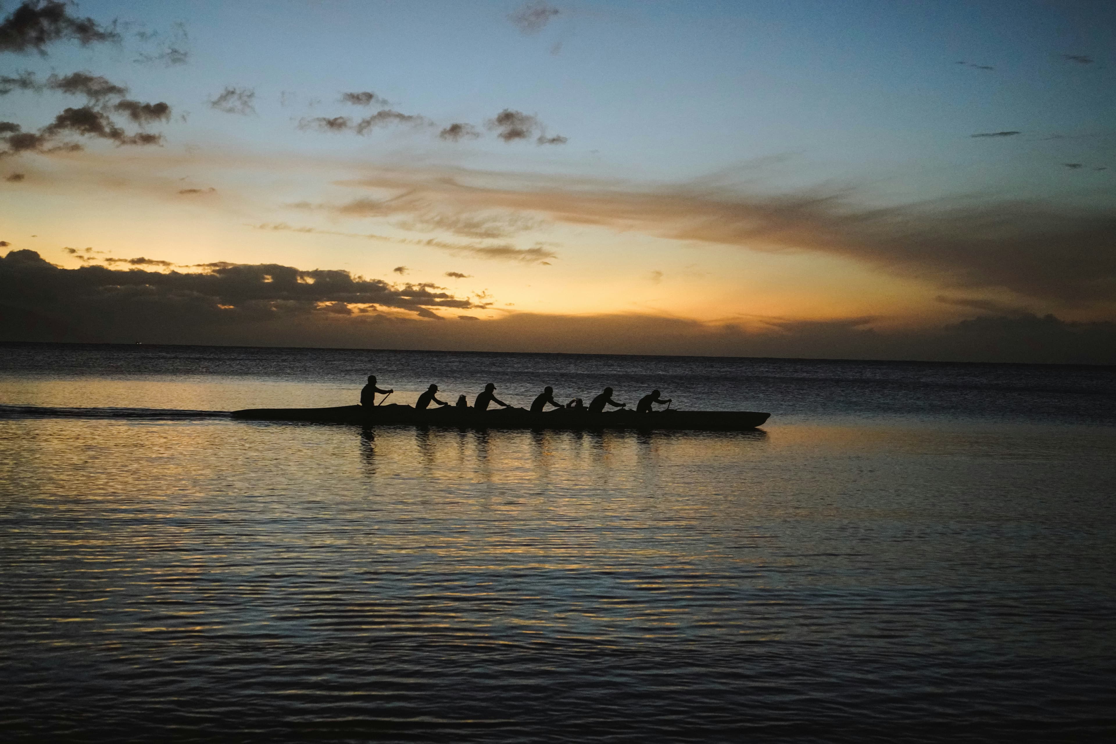 Une équipe qui rame ensemble au coucher du soleil